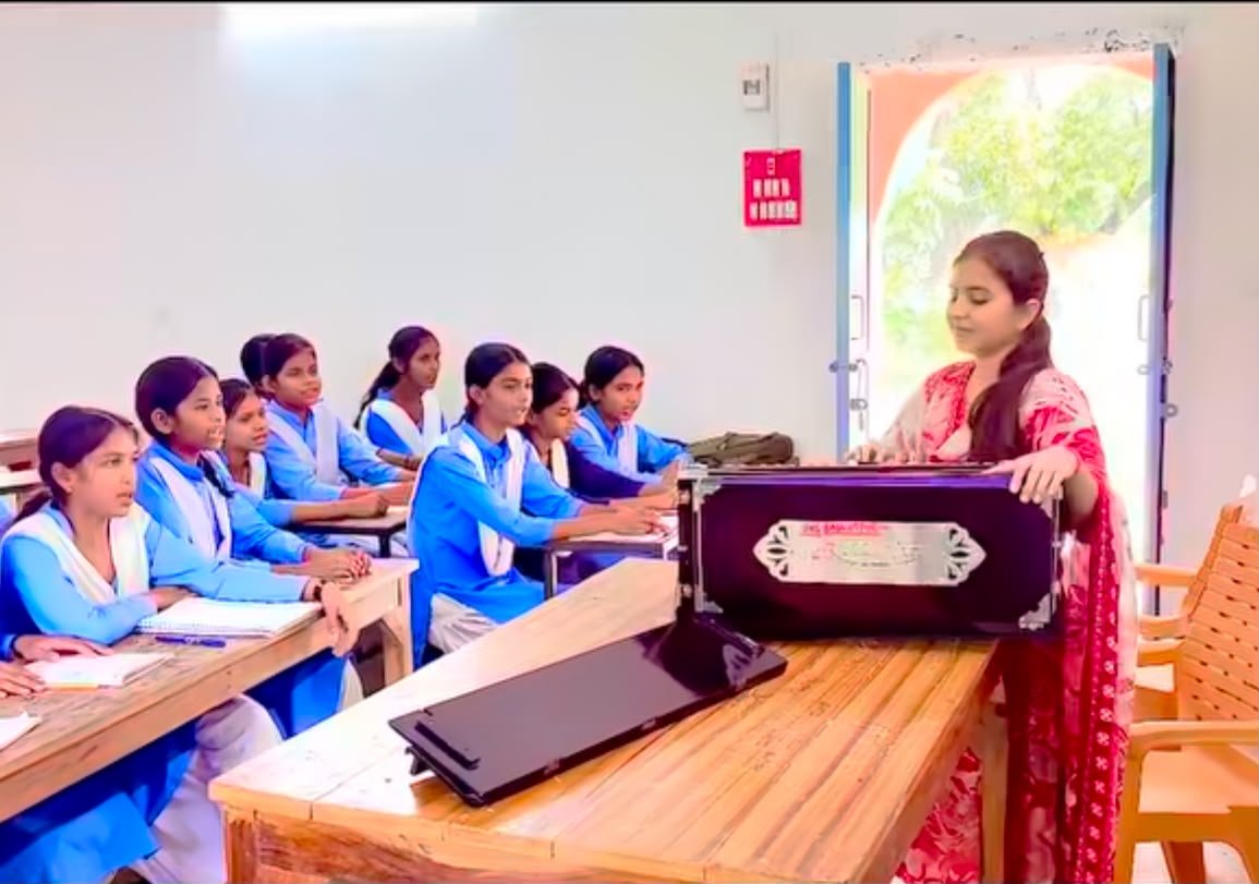 सुपौल की शिक्षिका श्रुति मौसम बच्चों को हारमोनियम के साथ भजन सिखाते हुए